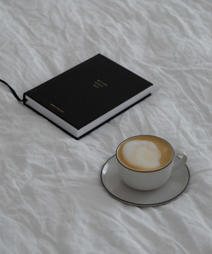 better every day journal rests on a bed next to a cup of coffee
