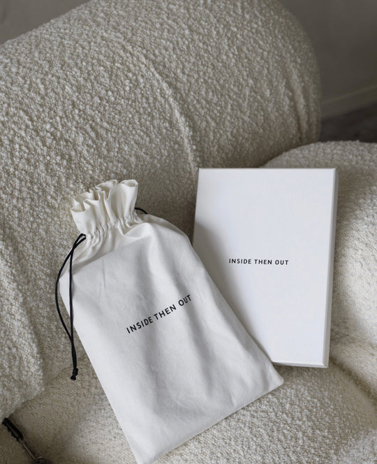 The Inside Then Out official packaging and dust bag placed on a cream couch