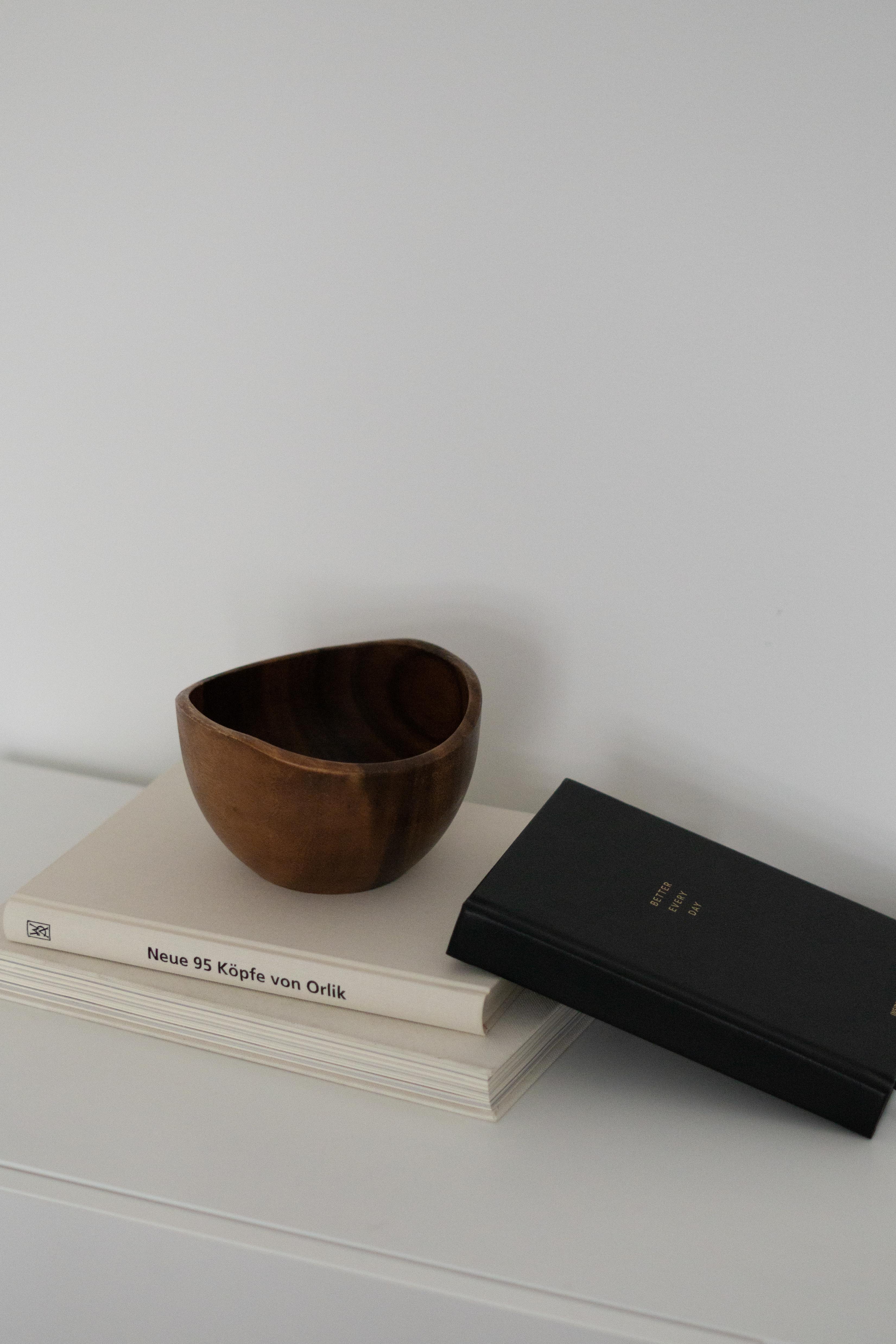 Better Every Day Journal lying on a table with two cream coffee table books and a brown wooden decor bowl 