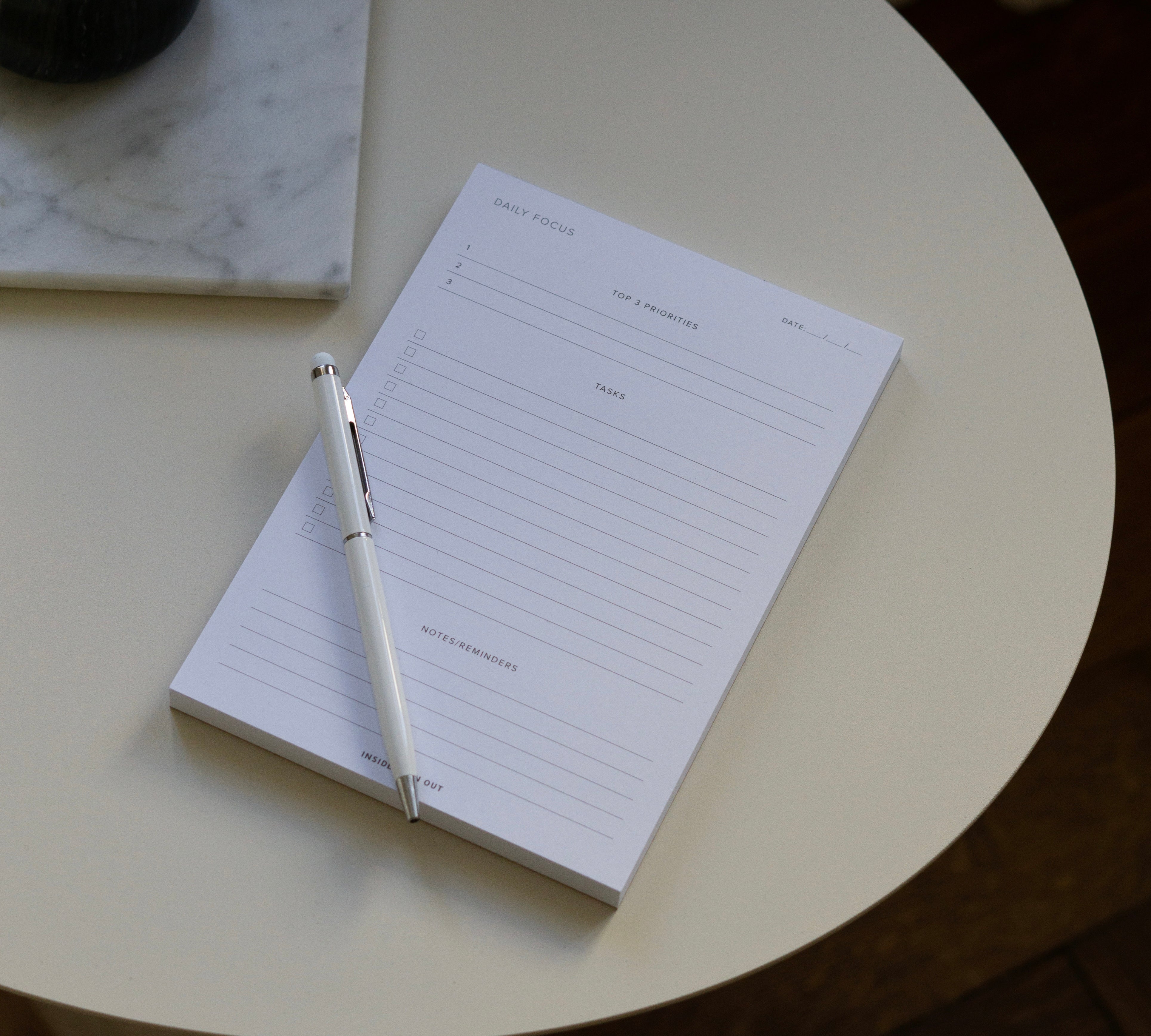 Daily Focus Notepad with pen on off-white table 