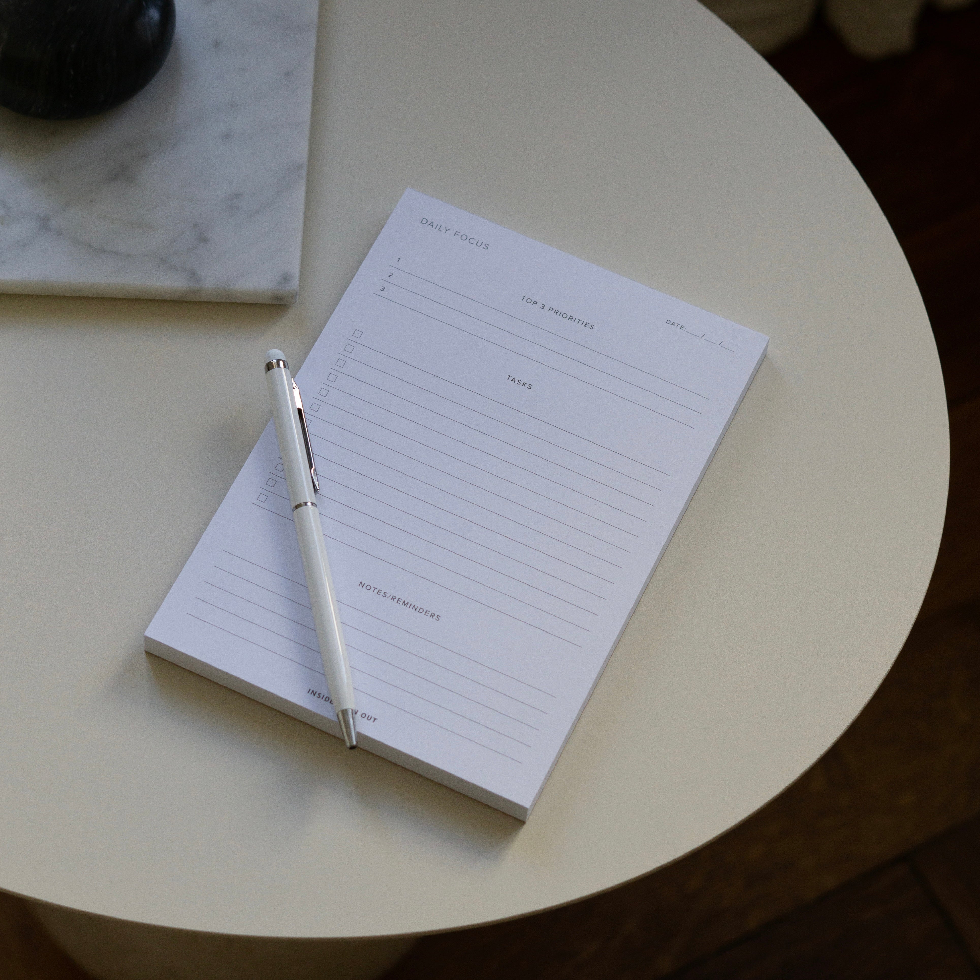 Daily Focus Notepad with pen on off-white table 