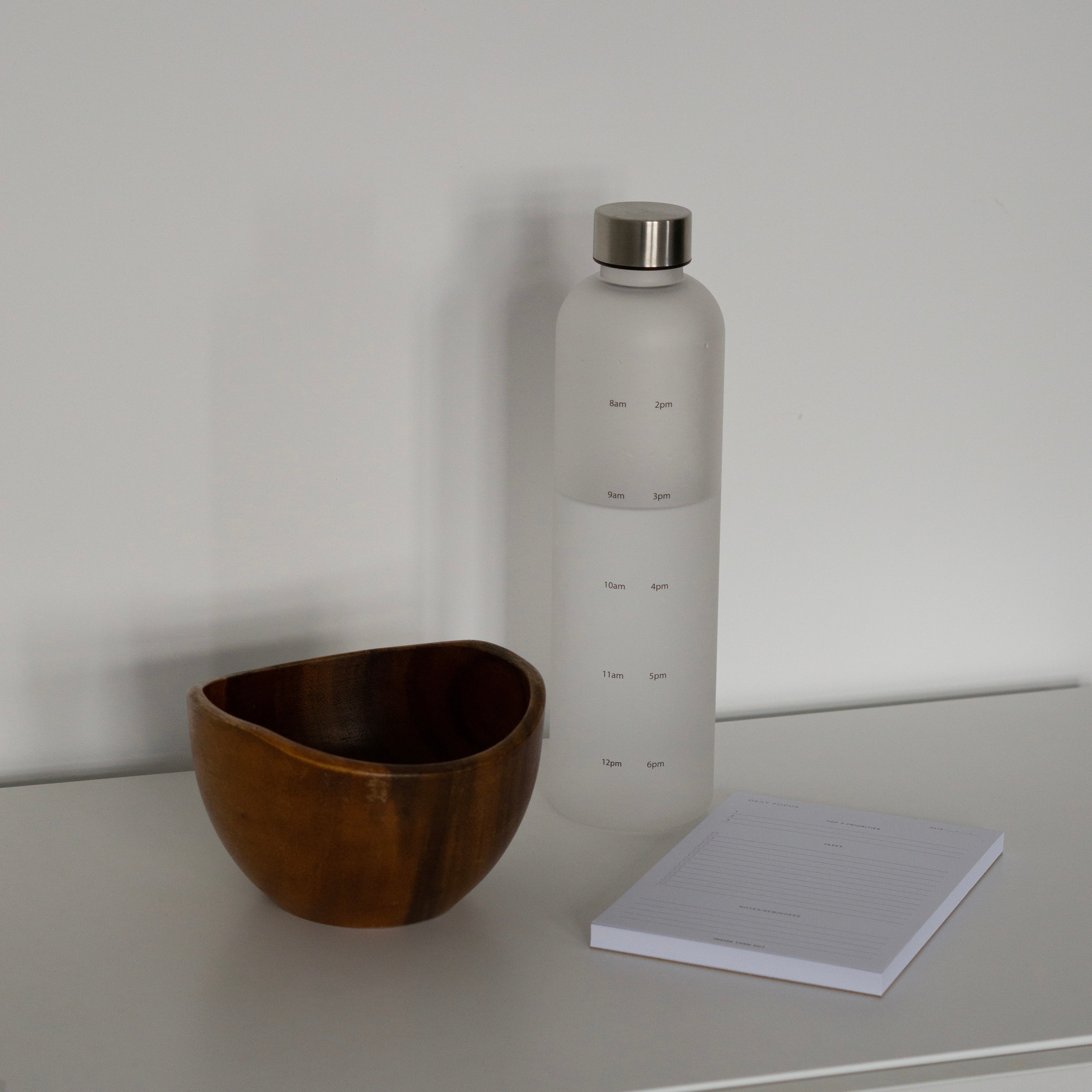 Daily Focus Notepad and Water Tracking Bottle on off-white table